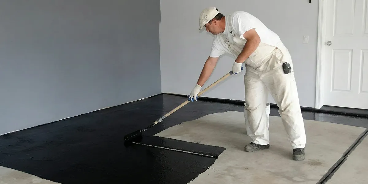 basement waterproofing professional applying waterproof coating to protect a basement floor in Omaha, NE